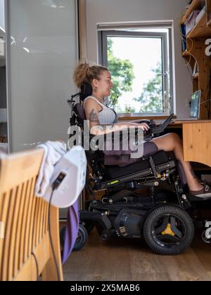 Woman in electric wheelchair working on laptop Stock Photo