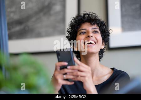 Young woman using smart phone in office Stock Photo