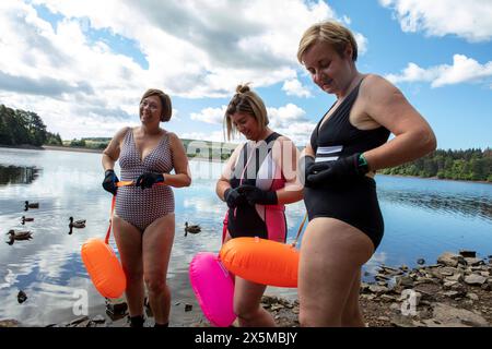 Female friends in swimsuits standing on rocky lakeshore, Yorkshire, UK Stock Photo