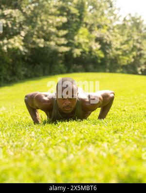 Athletic man doing push-ups on lawn in park Stock Photo