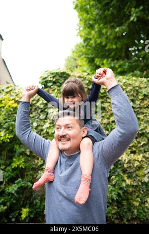 Smiling father carrying daughter on shoulders outdoors Stock Photo