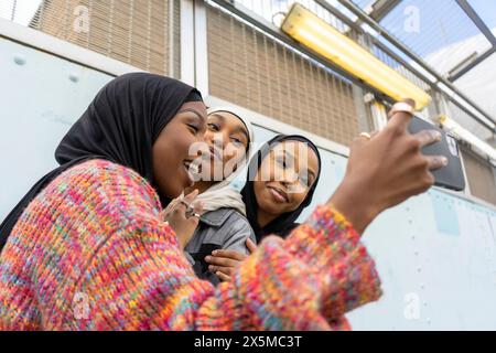 Smiling young women wearing hijabs taking selfie Stock Photo