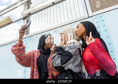 Smiling young women wearing hijabs taking selfie Stock Photo