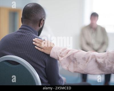 Woman consoling man in group therapy session Stock Photo