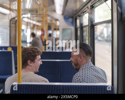 UK, South Yorkshire, Smiling gay couple talking in tram Stock Photo