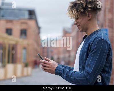 Smiling man using smart phone in city Stock Photo