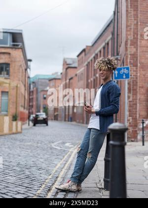 Smiling man using smart phone in city Stock Photo