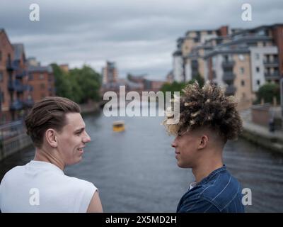 Young men standing on bridge and talking Stock Photo