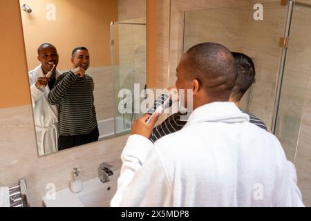 UK, London, Smiling gay couple brushing teeth in bathroom Stock Photo