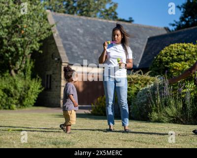 Mother with son (2-3) blowing soap bubbles Stock Photo