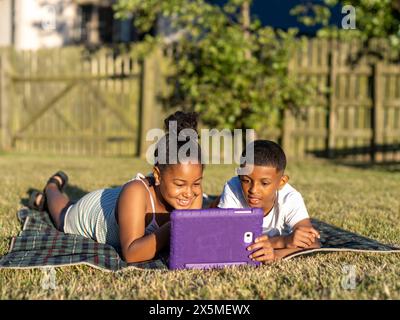 Siblings (8-9, 10-11) using tablet in back yard Stock Photo