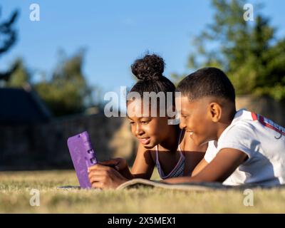 Siblings (8-9, 10-11) using tablet in back yard Stock Photo