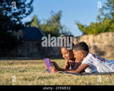 Siblings (8-9, 10-11) using tablet in back yard Stock Photo