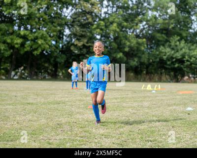 Children (8-9) dressed in uniforms practicing on soccer field Stock Photo