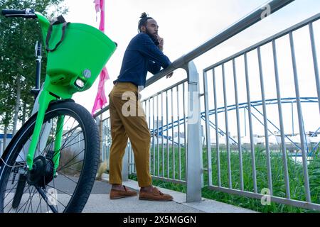 Businessman standing by rental bicycle and talking on phone Stock Photo