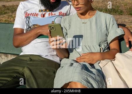 Couple sitting on bench and using smart phone Stock Photo