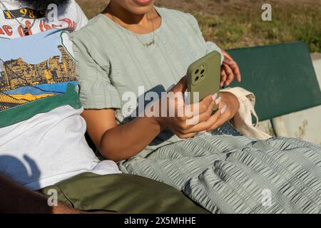 Couple sitting on bench and using smart phone Stock Photo