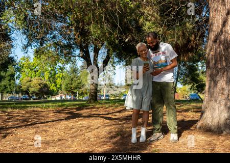 Couple using smart phone in park Stock Photo