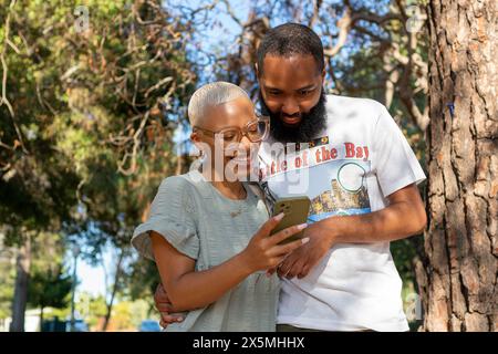 Couple using smart phone in park Stock Photo