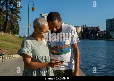 Couple using smart phone in city Stock Photo
