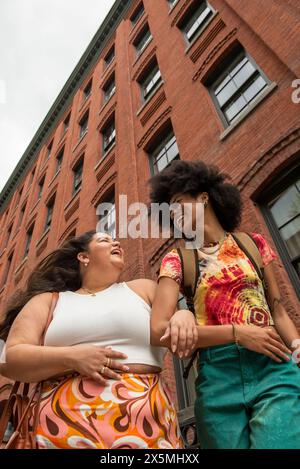 Two women in front of brick building, low angle view Stock Photo