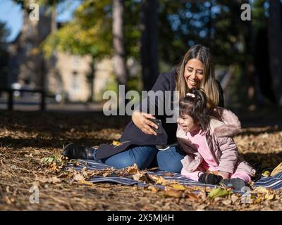 Mother and daughter with Down syndrome taking selfie in park Stock Photo