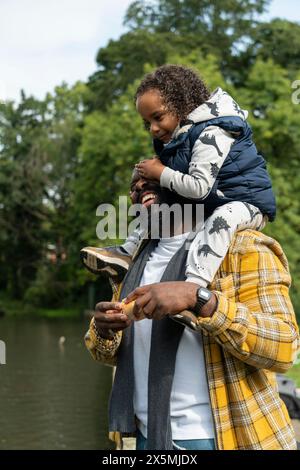 Smiling man carrying daughter on shoulders Stock Photo