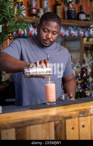 Bartender pouring cocktail into glass Stock Photo