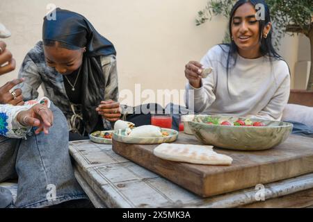 Friends wearing?hijabs?enjoying snacks on patio Stock Photo