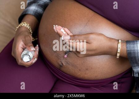 Pregnant woman?applying moisturizer on belly Stock Photo