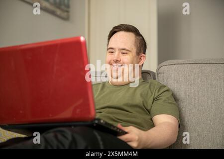 Man sitting on sofa and using laptop Stock Photo