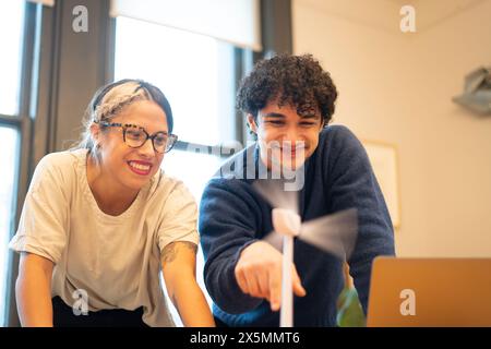 Engineers spinning wind turbine model in office Stock Photo