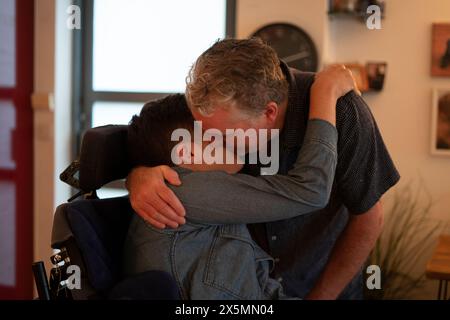 Father embracing disabled son at home Stock Photo