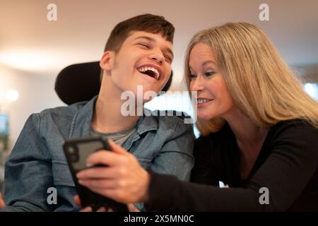 Mother using smartphone with disabled son Stock Photo