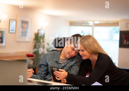 Mother using smartphone with disabled son Stock Photo