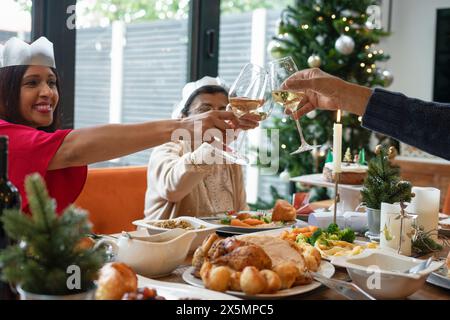 Family wearing paper crowns toasting during Christmas dinner Stock Photo