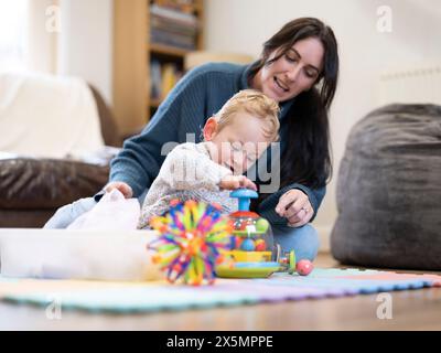 Mother looking at son playing with toys Stock Photo