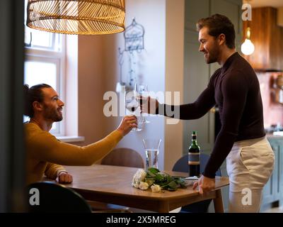 Gay couple making wine toast at home Stock Photo
