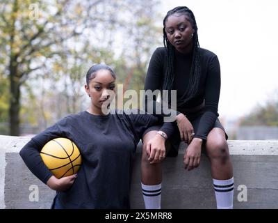 Portrait of female friends outdoors holding basketball ball Stock Photo