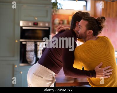 Gay couple embracing in kitchen Stock Photo