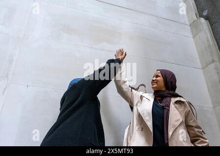 Two women wearing hijabs doing high-five Stock Photo