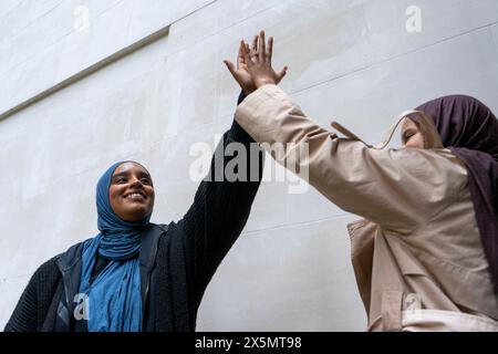 Two women wearing hijabs doing high-five Stock Photo