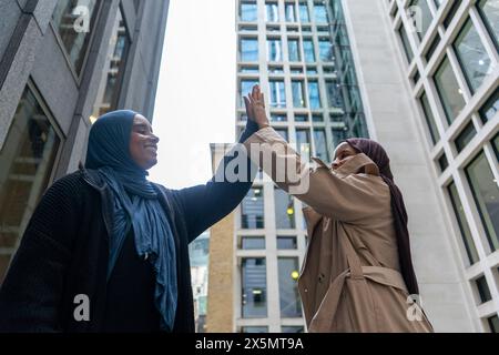 Two women wearing hijabs doing high-five Stock Photo