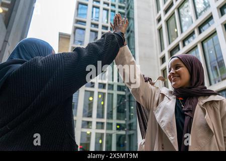 Two women wearing hijabs doing high-five Stock Photo