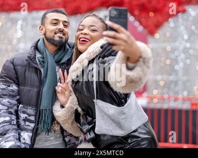Young couple taking selfies against Christmas decorations Stock Photo