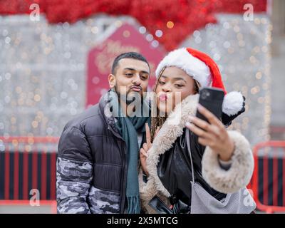 Young couple taking selfies against Christmas decorations Stock Photo
