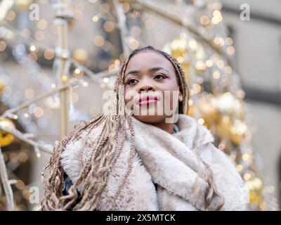 Young woman standing against Christmas decorations Stock Photo