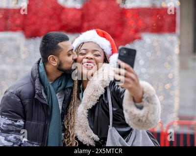 Young couple taking selfies against Christmas decorations Stock Photo