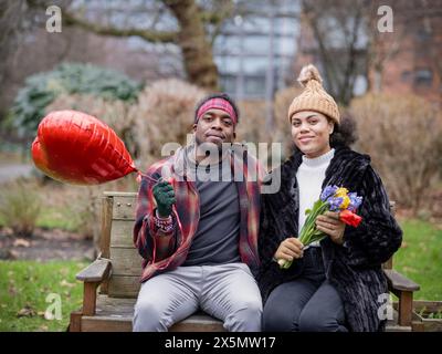 Portrait of smiling couple with heart shaped balloon and flowers Stock Photo