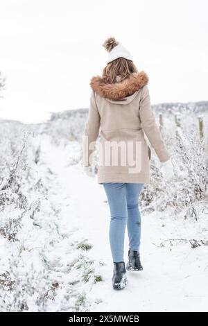 Rear view of woman walking in snowy landscape Stock Photo